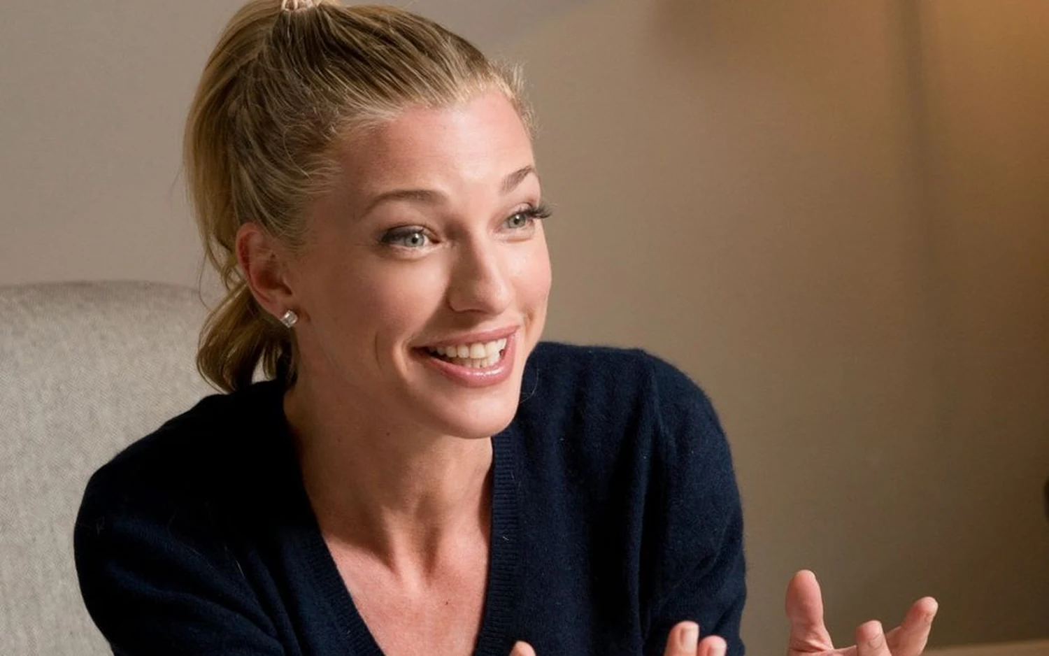Nicole Junkermann laughing mid conversation in a navy knit, seated in a pale room Nicole Junkermann laughing mid conversation in a navy knit, seated in a pale room